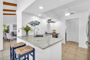 A modern kitchen with a granite countertop, a built-in sink, and a stainless steel range hood.