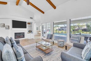 A modern living room with a glass coffee table, grey sofas, and a fireplace.