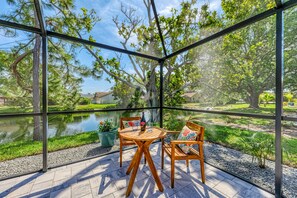 Varanda envidraçada com mesa e cadeiras, com vista para um lago e vegetaç ão.