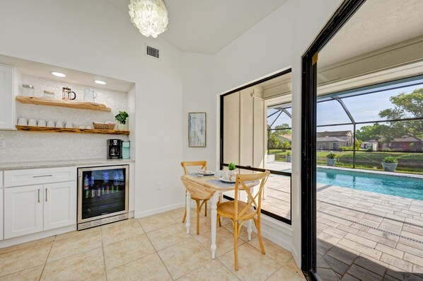 A kitchen with a built-in refrigerator, a coffee machine, and a dining area with a table and chairs.