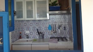 Una cocina con gabinetes blancos, salpicadero de azulejos y estufa a gas.