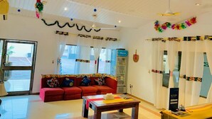 Una habitación amplia con un sofá rojo, una mesa de madera y un ventilador de techo.