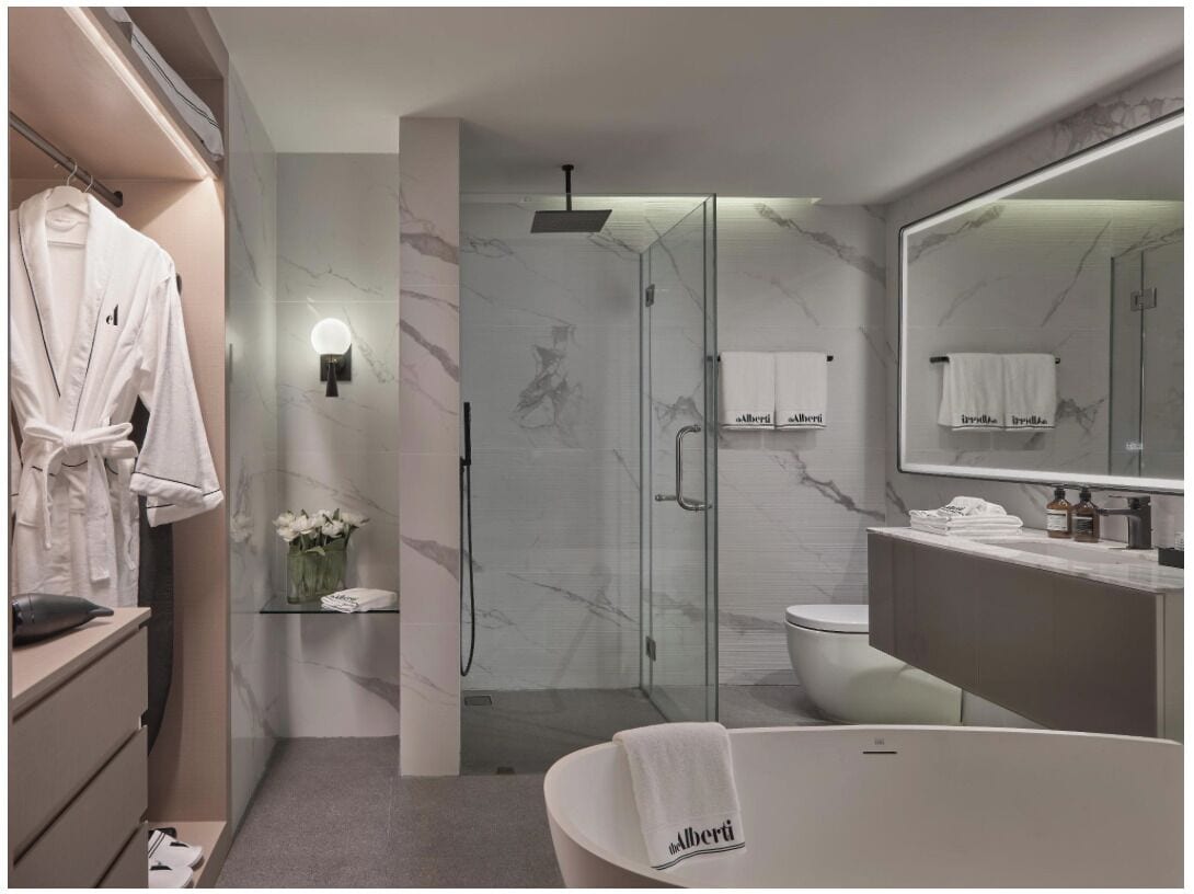 A modern bathroom with a glass-enclosed shower, a white bathtub, and a vanity with a mirror.