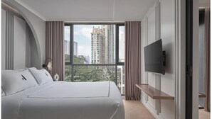 A modern hotel room with a large bed, a flat-screen TV mounted on the wall, and a balcony with a city view. - The Alberti (Bangkok)