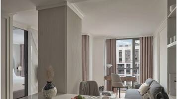 Una habitación de hotel moderna con comedor, sofá y vista a la ciudad.