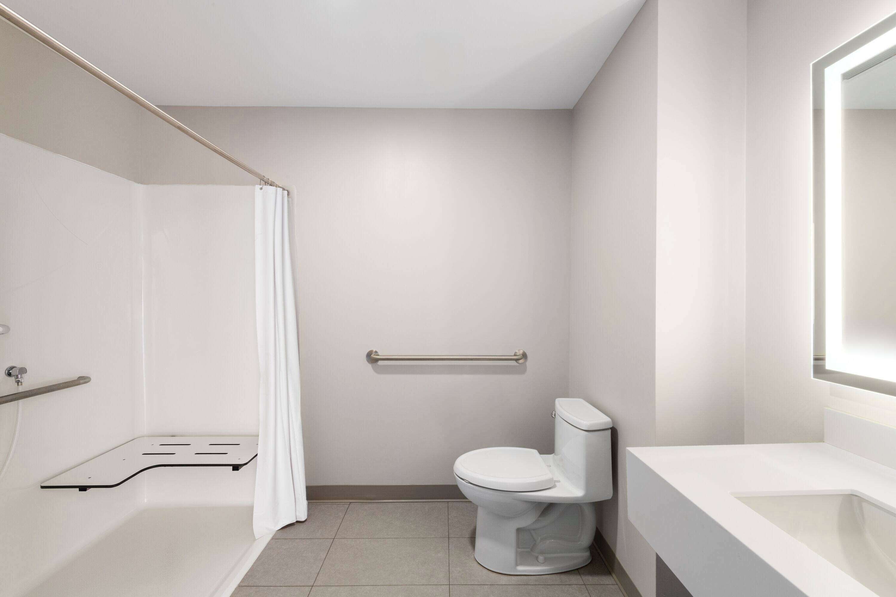 Une salle de bain moderne équipée d’une baignoire, de toilettes et d’un rideau de douche.