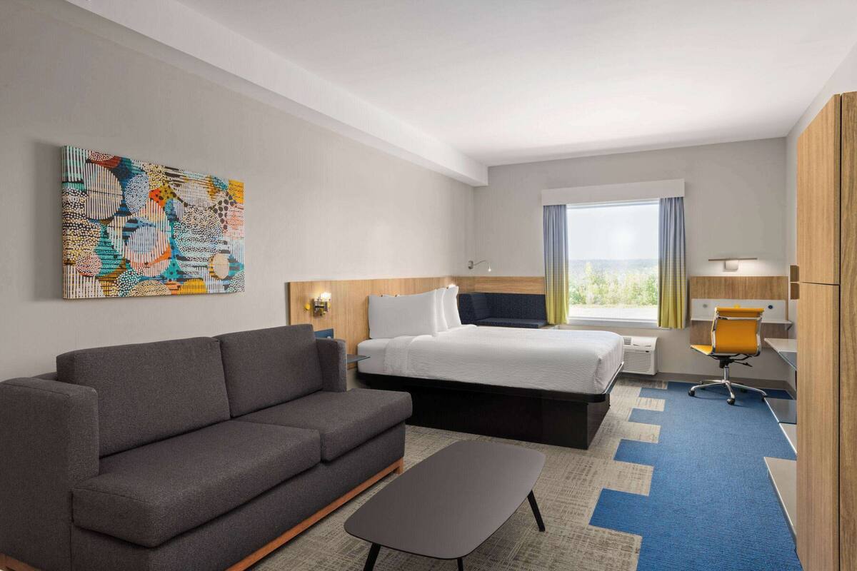 A hotel room with a sofa, a bed, a desk, and a chair.