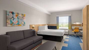 Una habitación de hotel con sofá, cama, escritorio y una silla.