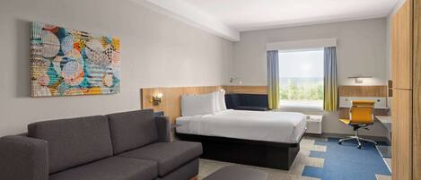 A hotel room with a sofa, a bed, a desk, and a chair.