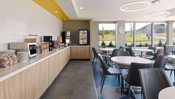 A modern cafe with a long counter, seating area, and large windows.