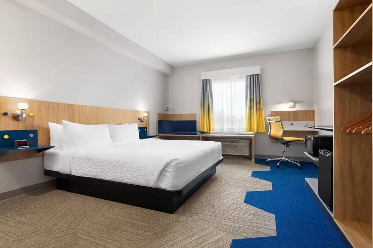 A hotel room with a bed, desk, chair, and wardrobe.