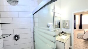 Un baño moderno con cabina de ducha de vidrio, lavabo con encimera y espejo.