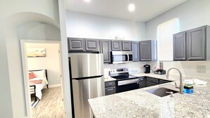 Una cocina moderna con gabinetes grises, electrodomésticos de acero inoxidable y encimera de granito.