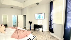 Un dormitorio con una cama, un escritorio y un televisor en la pared.