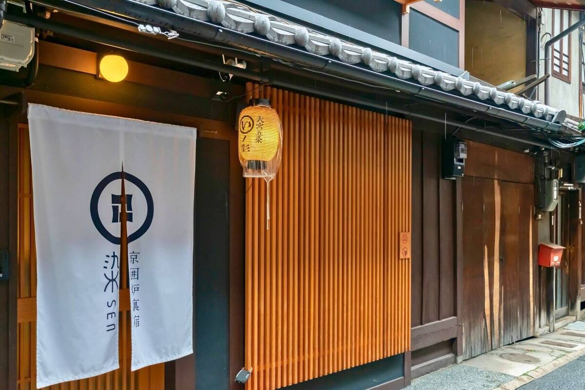 Un edificio tradicional japonés con fachada de madera, un letrero con caracteres japoneses y un farol colgante.