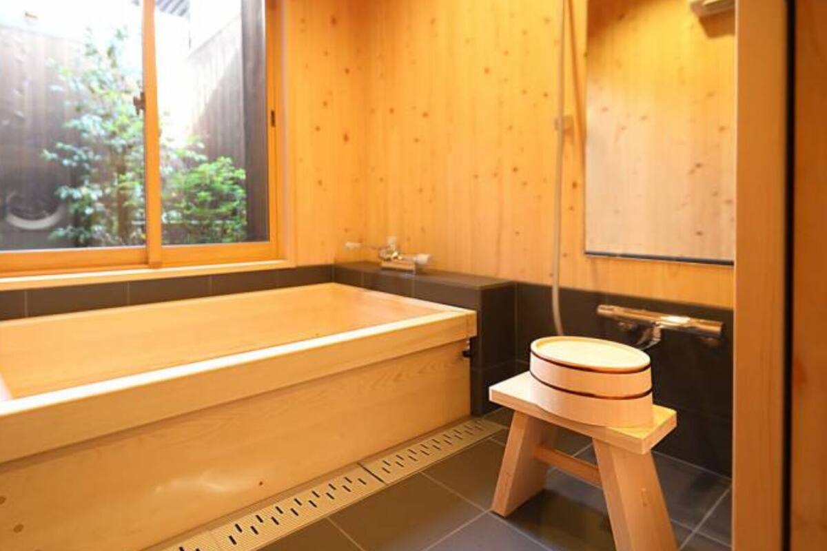 Un baño de estilo cabaña de madera con una bañera, un taburete pequeño y una ventana.