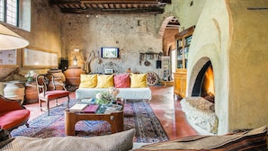 A rustic living room with a stone fireplace, wooden furniture, and a traditional rug. - Luxury, Sustainability and Eco Pool in Frangi Apt. (Certaldo)