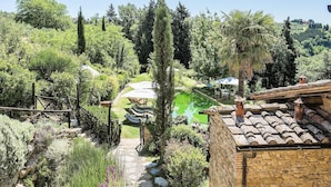 A garden with a pond, stone pathway, and outdoor seating area. - Luxury, Sustainability and Eco Pool in Frangi Apt. (Certaldo)