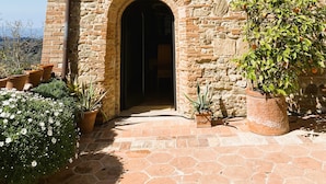 A stone building with an arched entrance, potted plants, and a clear sky. - Luxury, Sustainability and Eco Pool in Frangi Apt. (Certaldo)