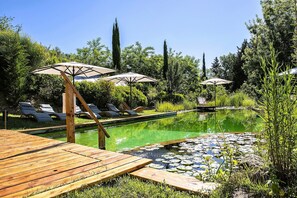 A serene outdoor pool area with lounge chairs and umbrellas, surrounded by lush greenery and a wooden deck. - Luxury, Sustainability and Eco Pool in Frangi Apt. (Certaldo)