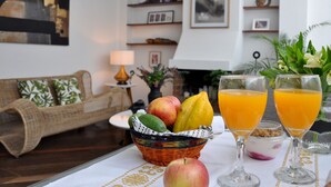 Ein Wohnzimmer mit einer Couch, einem Tisch mit Früchten und Getränken sowie einem Kamin.