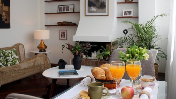 Ein Frühstückstisch mit Croissants, Orangensaft und einem Buch.