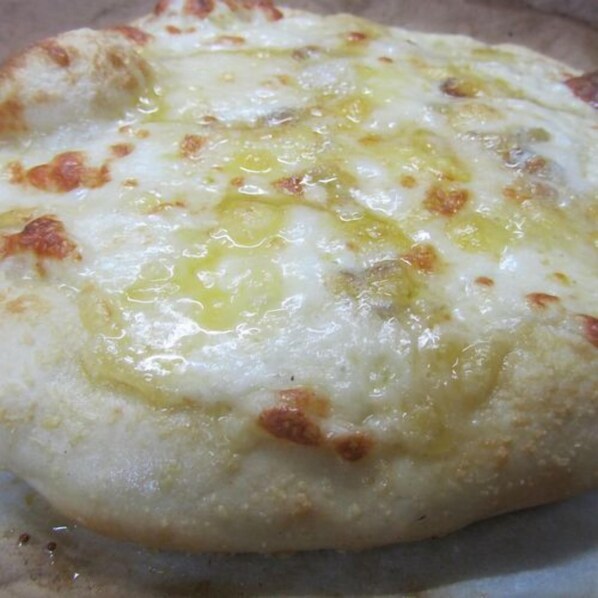 A close-up of a pizza with melted cheese and visible oil on a surface.