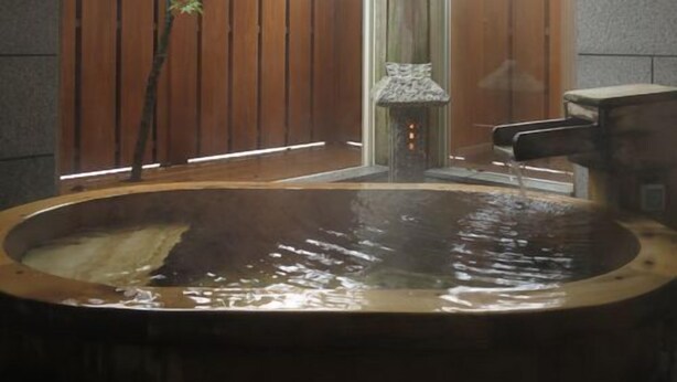 Un bain à remous entouré de pierres, une clôture en bois et un mur en pierre.
