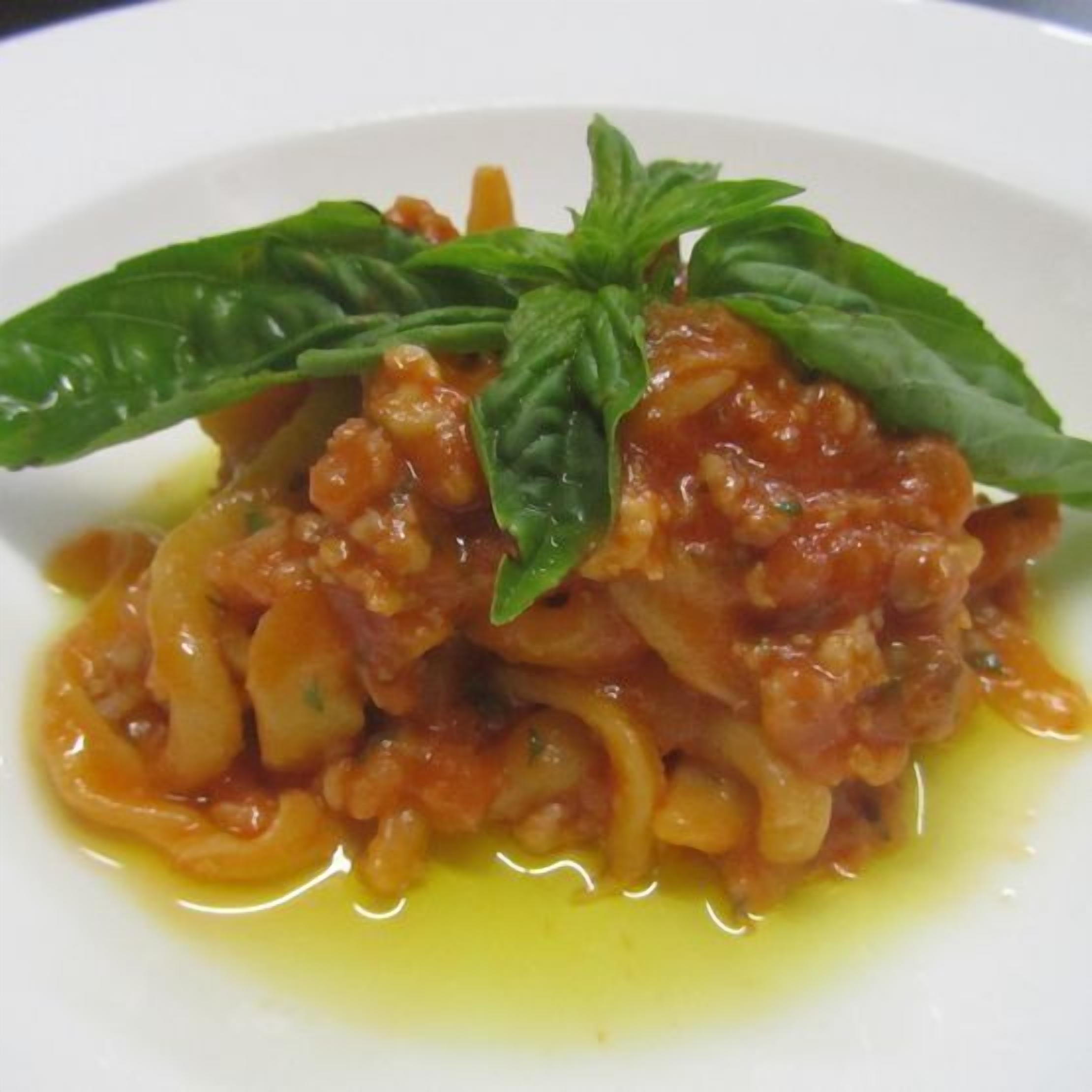 A plate of pasta with a tomato-based sauce and basil garnish.