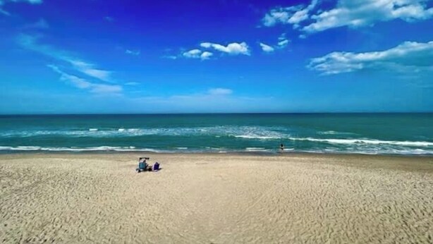 Une plage avec un ciel dégagé et une mer calme.