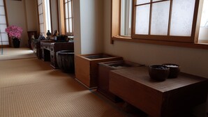 A traditional Japanese room with tatami flooring, a low wooden table, and a window with shoji screens.