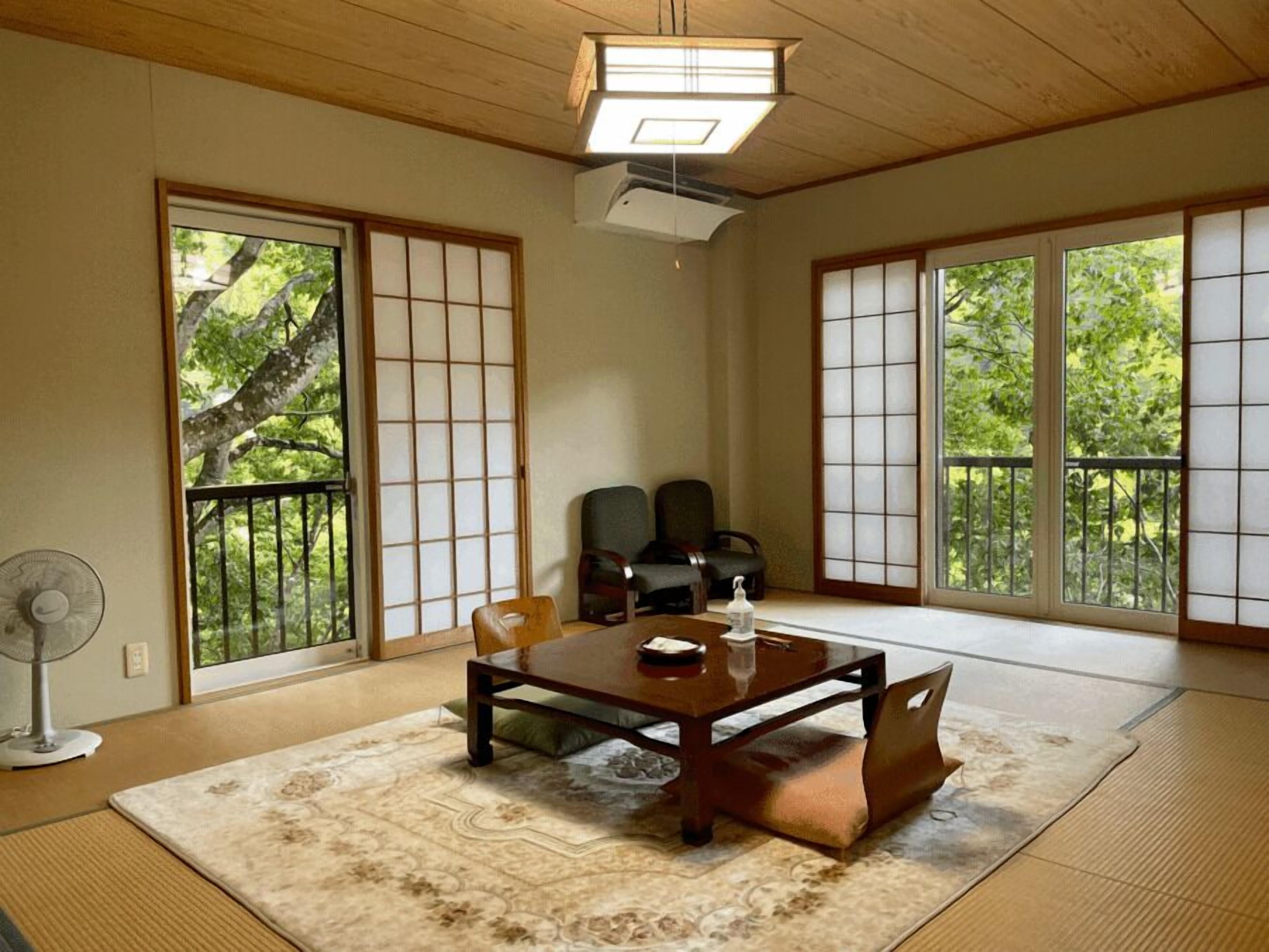 A traditional Japanese room with tatami flooring, sliding doors, and a low table with cushions.