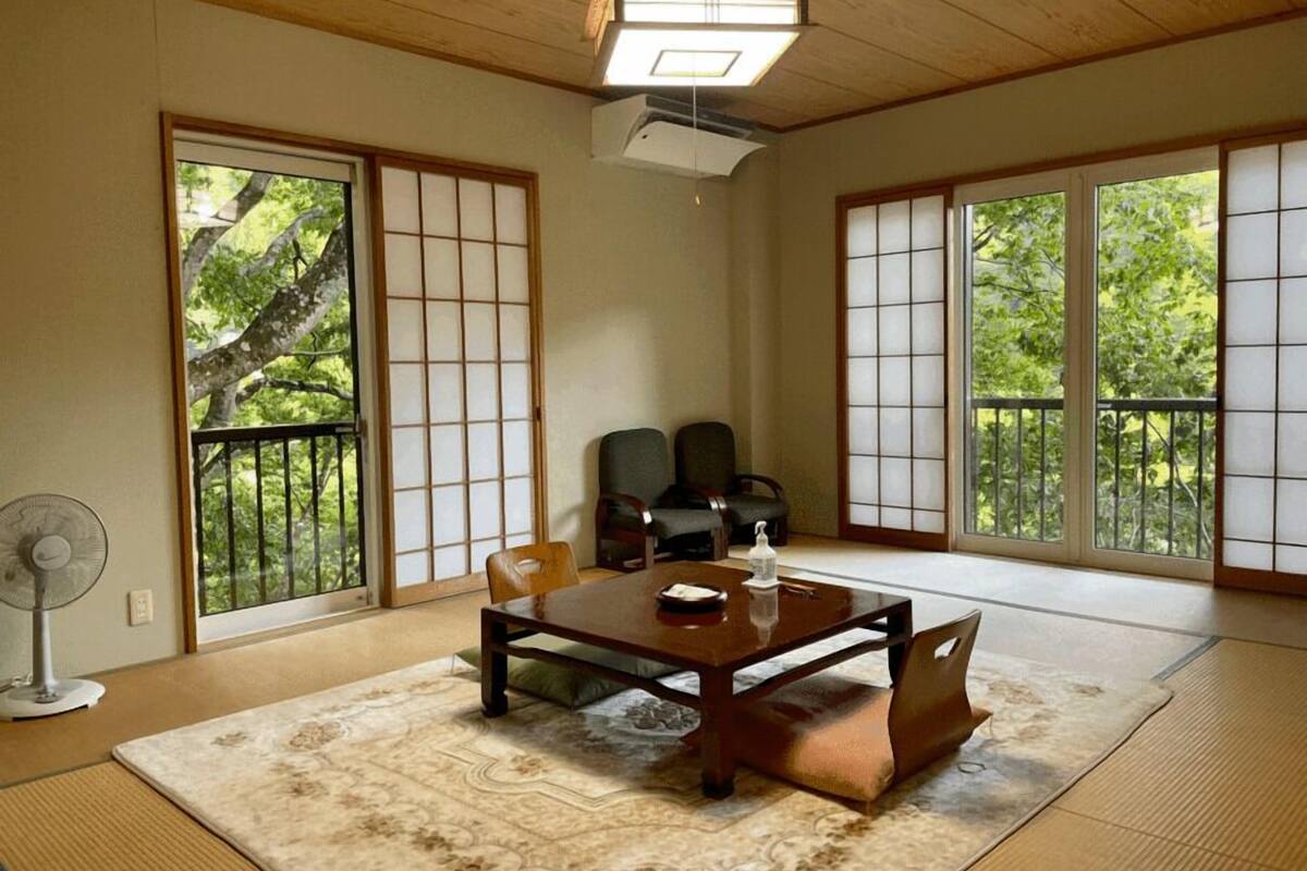 Una habitación japonesa tradicional con suelo de tatami, puertas correderas y una mesa baja con cojines.
