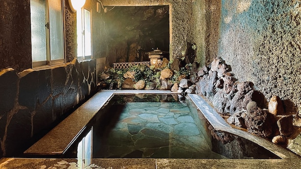 A stone pool with a stone wall and a window.