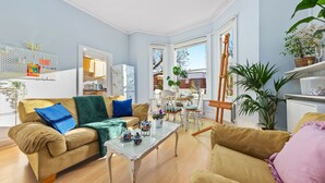 A living room with a beige sofa, a glass coffee table, and a dining area with a white table and chairs.