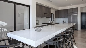 Une cuisine moderne dotée d’un grand îlot central, de tabourets de bar et d’appareils électroménagers en acier inoxydable.