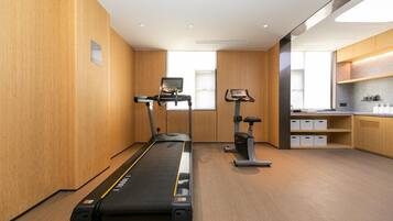 Ein modernes Hotelzimmer mit Laufband, Ergometer und einer Küchenzeile.