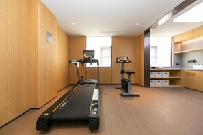 Una habitación de hotel moderna con una cinta de correr, bicicleta estática y una zona de kitchenette.
