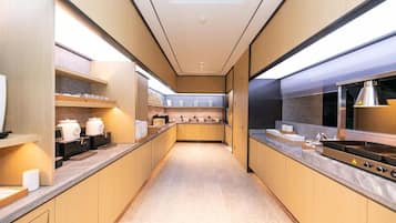 A modern kitchen with wooden cabinets, stainless steel appliances, and a long countertop.
