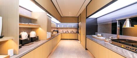 A modern kitchen with wooden cabinets, stainless steel appliances, and a long countertop.