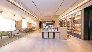 Un moderno vestíbulo de hotel con mostrador de recepción, zona de estar y estanterías.
