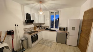A compact kitchen with white cabinets, a built-in oven, a microwave, and a dishwasher. - Cosy apartment (Villemurlin)