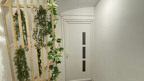 A hallway with a wooden plant wall, a white door, and a black carpet. - Cosy apartment (Villemurlin)