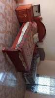 Una habitación con una cama, un armario de madera y una mesita.