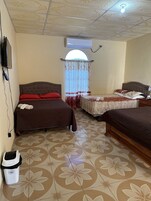 Habitación de hotel con dos camas, televisión, aire acondicionado, ventana con cortina y un cubo de basura.