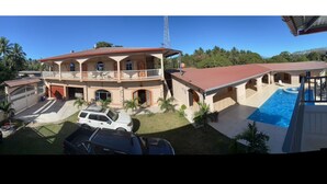 A two-story house with a swimming pool, a covered patio, and a satellite dish.