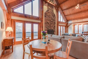 A cozy interior with a stone fireplace, wooden beams, and large windows. - Spacious Virginia Vacation Rental w/ Yard & Sauna (Purcellville)