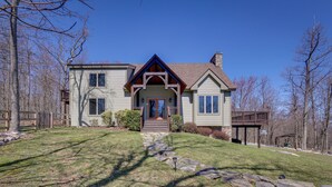 A two-story house with a stone pathway leading to the front door, surrounded by trees and a wooden deck. - Spacious Virginia Vacation Rental w/ Yard & Sauna (Purcellville)