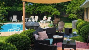 A poolside area with wicker furniture, a barbecue grill, and a welcome sign. - Remodeled House with Pool on Quiet cul-de-sac!  Walk to beach on Bay! (Shalimar)