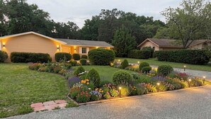 A residential house with a well-maintained lawn, a driveway, and a variety of flowering plants. - Remodeled House with Pool on Quiet cul-de-sac!  Walk to beach on Bay! (Shalimar)